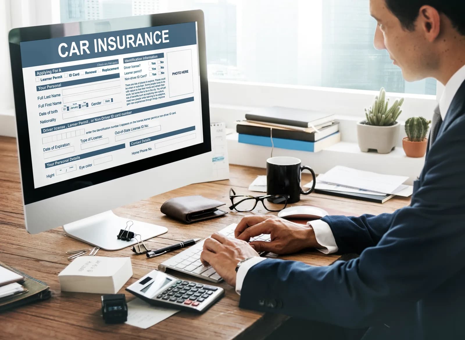 A computer screen showing a car insurance form on an office desk