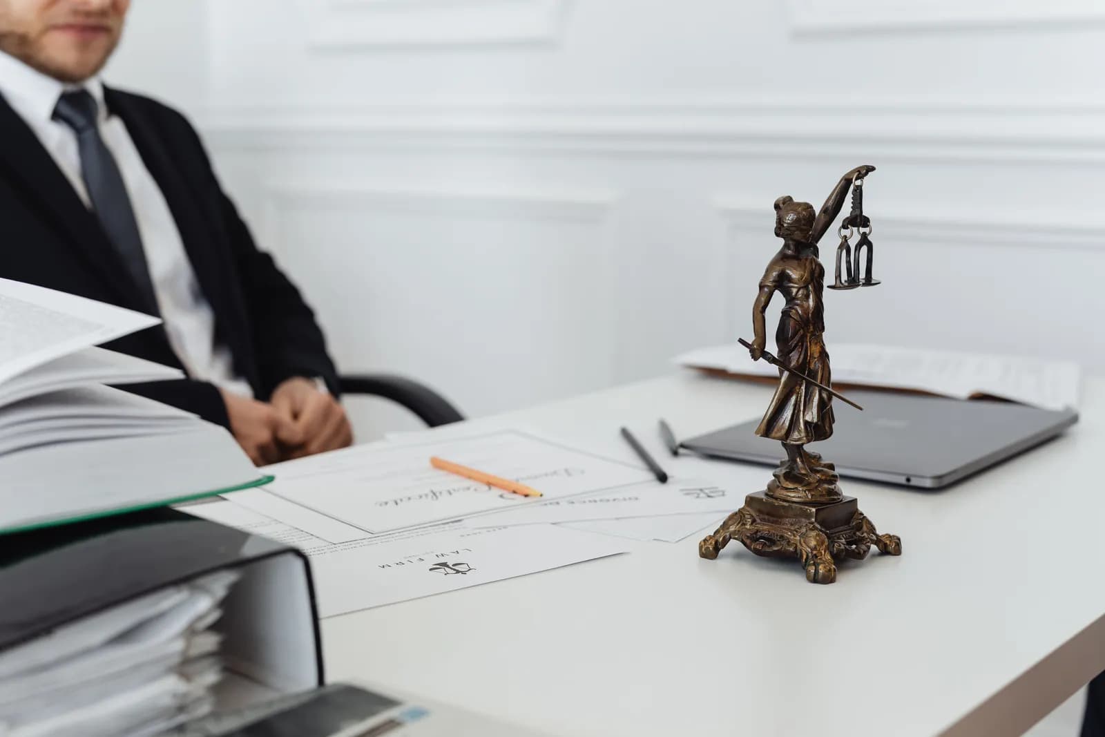 Documents and a small statue of Lady Justice on an office desk