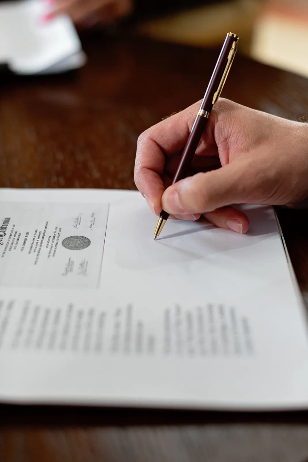 A hand signing a document with a fountain pen