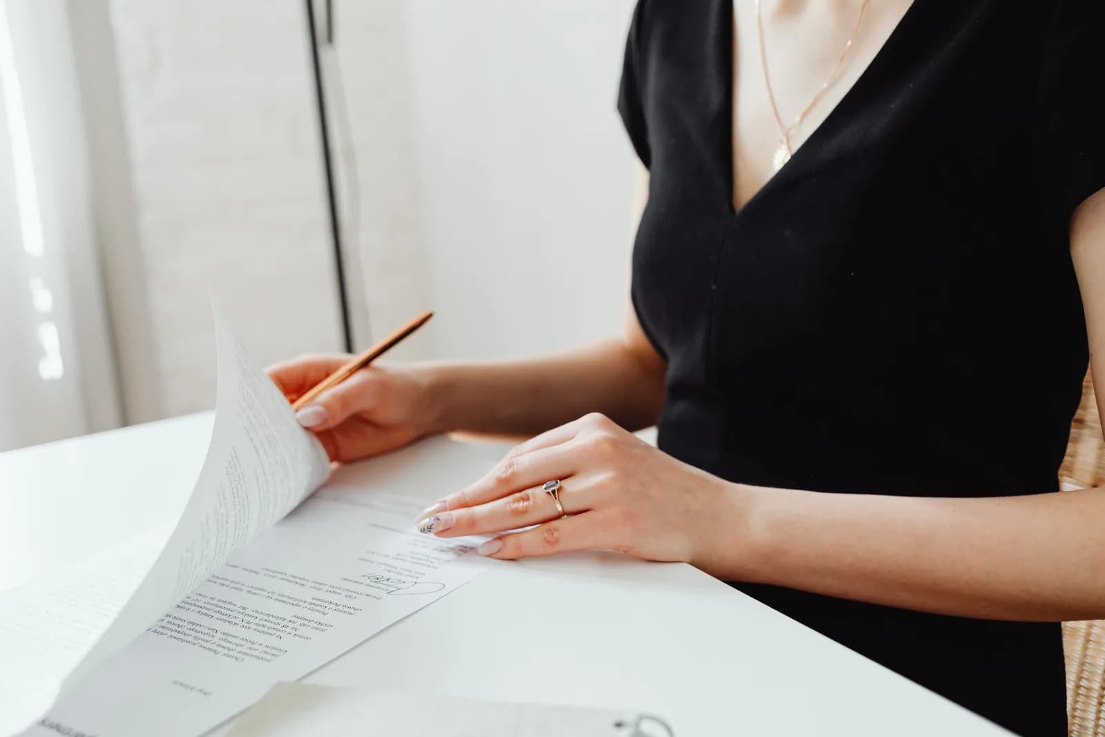 A person signing a paper at a white desk